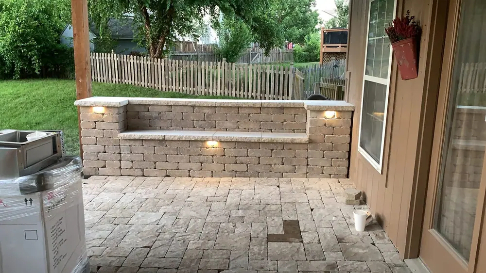 Paver patio and seat wall lit at dusk with warm built-in wall and step lighting