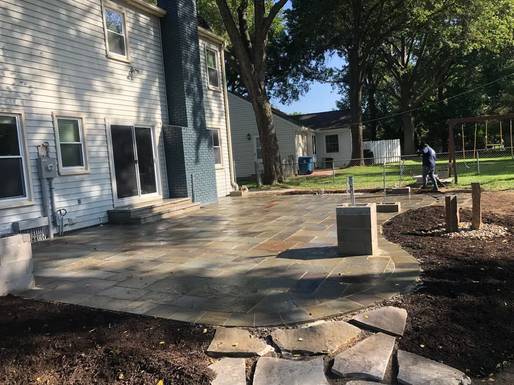New flagstone patio with stone edging behind a home