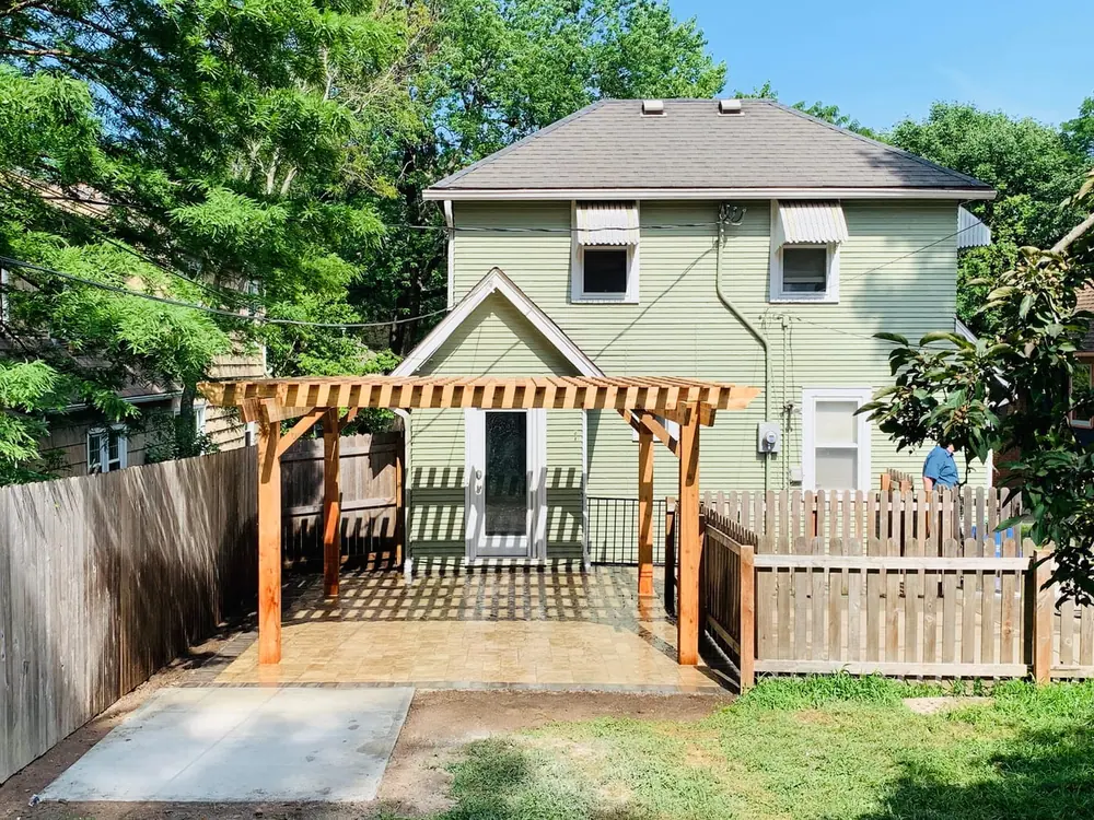 Cedar pergola over a deck with a white railing and a green lawn in front