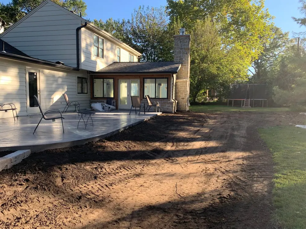 Backyard paver patio at dusk with the home lit up behind it