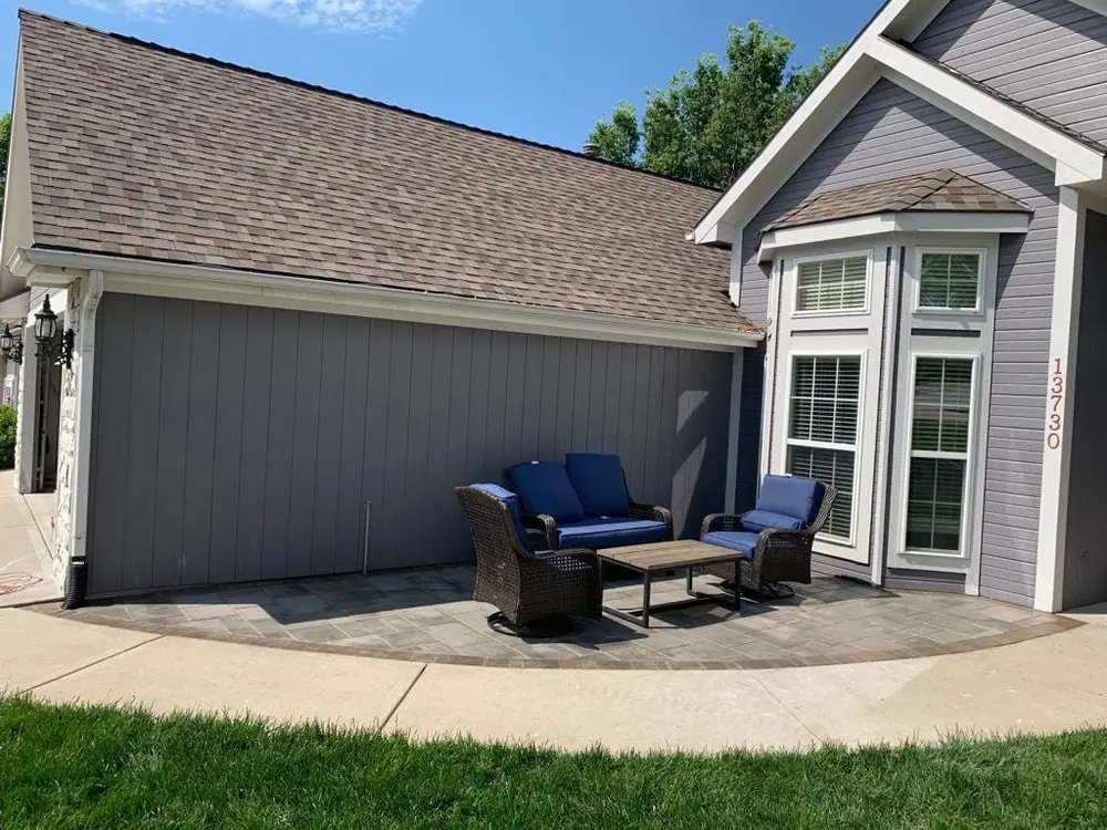 Backyard paver patio with a blue outdoor sofa set against the back of a home