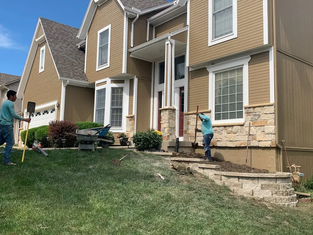 Backyard landscape install in progress with fresh sod and beds behind a home
