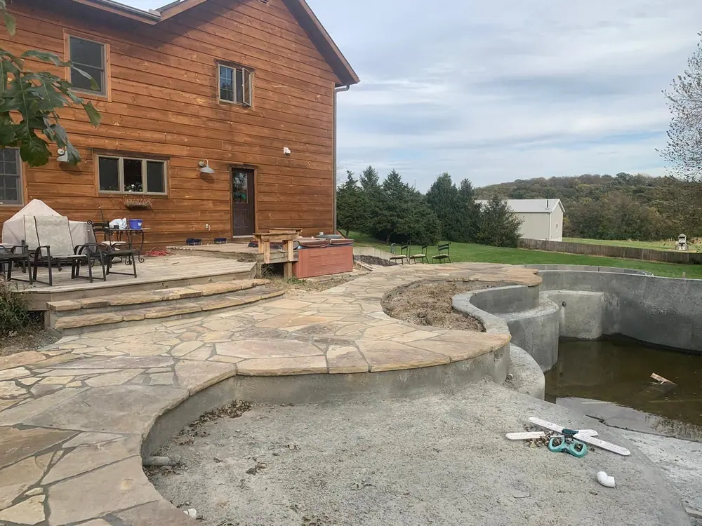 Flagstone patio with large stone boulders being placed behind a home