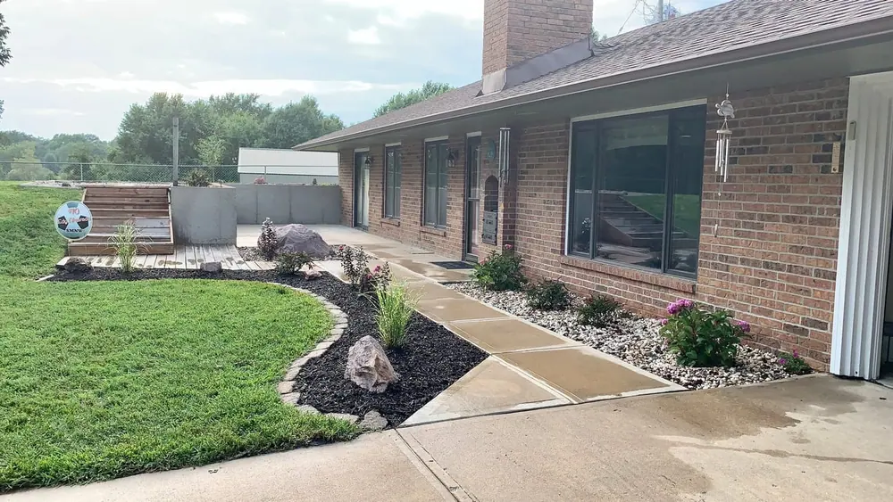 Circular stone fire-pit seating area on a lawn behind a home with a screened porch